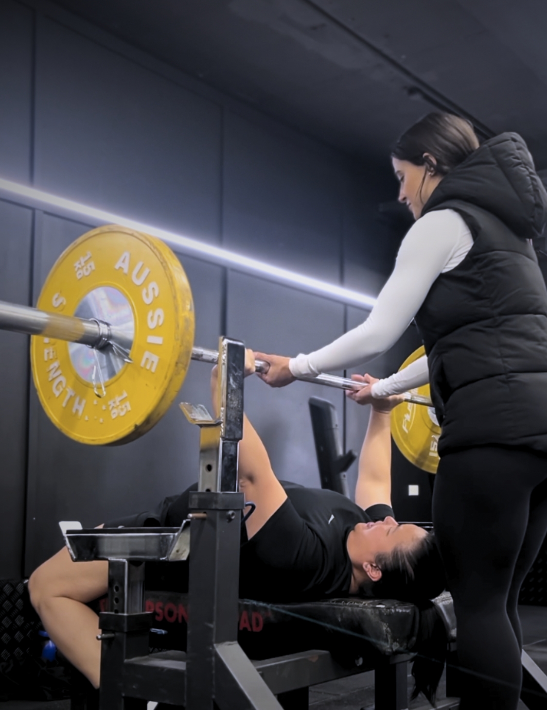 Samantha Lourens coaching a client through a bench press at Riley’s Gym